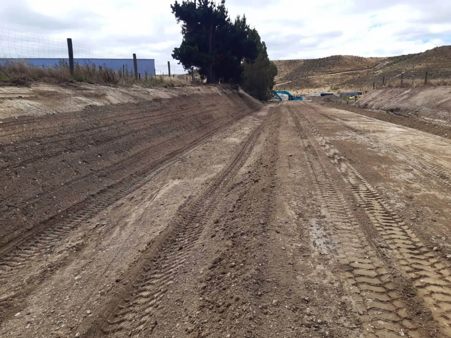 A dirt road bordered by a fence